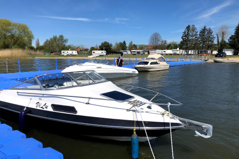 Både fortøjet ved en flydende bro ved Holiday home Inselblick i Nowe Warpno, Tyskland, med campingvogne i baggrunden.