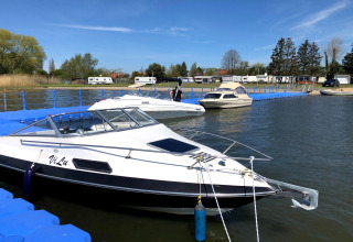 Boats moored at a floating dock at Holiday home Inselblick in Nowe Warpno, Germany, with caravans in the background.