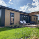 Eksteriør af Zonneweelde Lodge Deluxe med moderne trædesign, solsenge og terrasse under stor parasol.