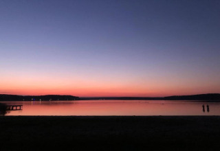 Atardecer sobre un lago en Holiday home «Maryna», Alemania, con dos personas y un muelle en silueta.