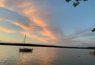 Zonsondergang aan een meer bij Holiday home 'Maryna' in Duitsland met zeilboot en mensen op de steiger.