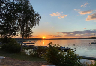 Tramonto su un lago tranquillo presso Holiday home «Maryna» in Germania con molo, barche e alberi visibili.