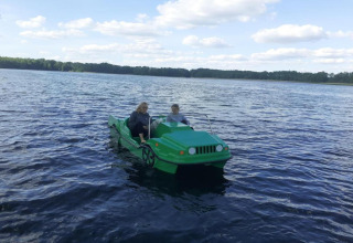 Twee personen in een groene waterfiets in de vorm van een auto op een meer bij Holiday home «Maryna» in Duitsland.