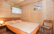 Dormitorio de madera con cama doble, silla, mesilla y arte de concha en Domki letniskowe Pobierowo.