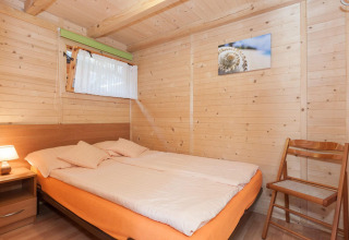 Camera da letto in legno con letto matrimoniale, sedia, comodino e quadro presso Domki letniskowe Pobierowo.