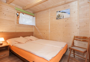 Gezellige houten slaapkamer met tweepersoonsbed, stoel, nachtkastje en schilderij in Domki letniskowe Pobierowo.