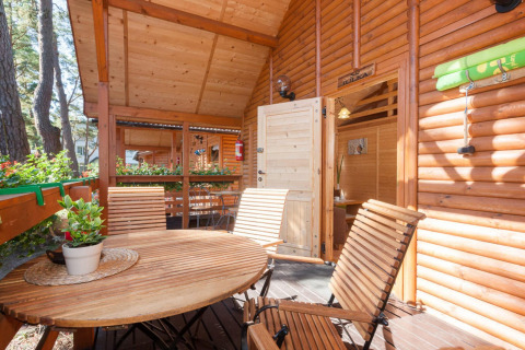 Terrazza in legno con tavolo e sedie al Domki letniskowe Pobierowo, immersa nel verde in Germania.