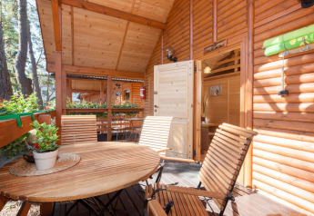 Udendørs træterrasse med bord og stole ved Domki letniskowe Pobierowo i Tyskland, omgivet af natur.