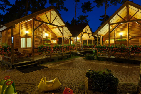 Vista serale di bungalow in legno illuminati con fiori a Domki letniskowe Pobierowo in Germania.