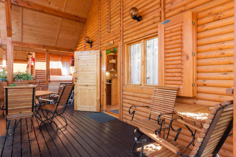 Veranda in legno al Domki letniskowe Pobierowo, con sedie e tavoli rustici immersi nella luce calda.