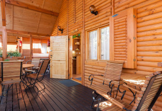Veranda in legno al Domki letniskowe Pobierowo, con sedie e tavoli rustici immersi nella luce calda.
