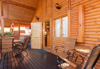Veranda van houten chalet met zitjes bij Domki letniskowe Pobierowo, baadt in warm zonlicht.