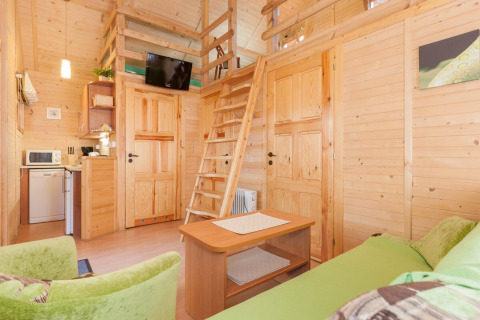 Vista interna di Domki letniskowe Pobierowo, accogliente lodge in legno con soppalco, salotto e angolo cottura.