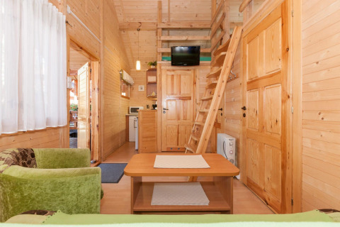 Interno di lodge in legno presso Domki letniskowe Pobierowo con soppalco, salotto e cucina a vista.