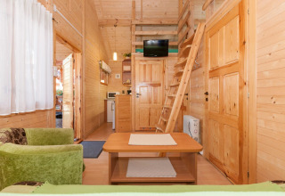 Interno di lodge in legno presso Domki letniskowe Pobierowo con soppalco, salotto e cucina a vista.