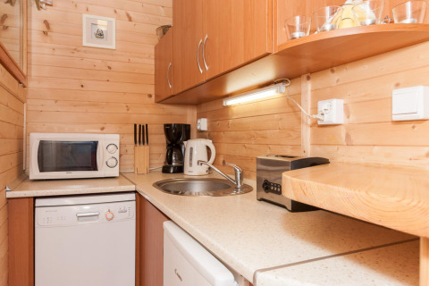 Piccolo angolo cottura in legno con microonde, macchina da caffè, bollitore e tostapane.