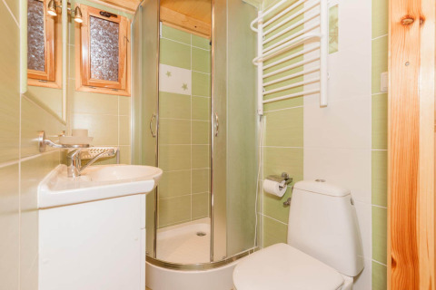 Bagno luminoso con piastrelle verdi, box doccia, lavabo piccolo, WC e scaldasalviette a Domki letniskowe Pobierowo.