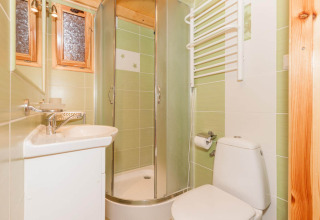 Bagno luminoso con piastrelle verdi, box doccia, lavabo piccolo, WC e scaldasalviette a Domki letniskowe Pobierowo.