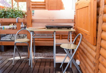 Pequeño espacio para comer al aire libre con dos sillas plegables y mesa junto a una cabaña en Domki letniskowe Pobierowo.