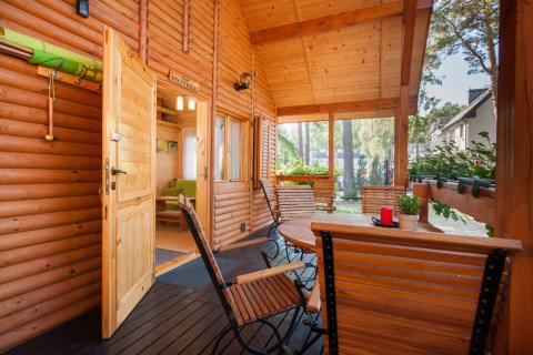 Veranda in legno con sedie e piante al lodge Domki letniskowe Pobierowo, atmosfera accogliente e solare.