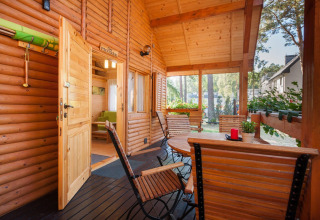 Veranda in legno con sedie e piante al lodge Domki letniskowe Pobierowo, atmosfera accogliente e solare.