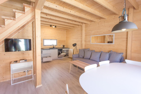 Modern en licht vakantiehuisje in hout te Pobierowo, Duitsland, met open keuken, zithoek en eettafel.