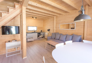 Modern en licht vakantiehuisje in hout te Pobierowo, Duitsland, met open keuken, zithoek en eettafel.