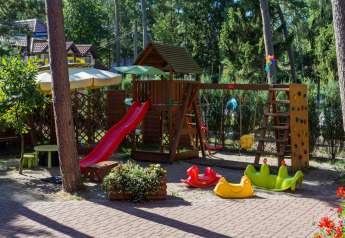 Un colorato parco giochi con scivolo, altalene e attrezzature a Domki letniskowe Pobierowo in Germania.