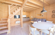 Lyst træferiehus med moderne køkken, spisebord, sofa, og trappe, beliggende i Pobierowo, Tyskland.
