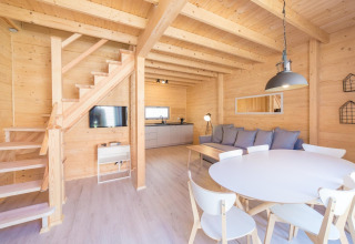 Lichte houten vakantiewoning met moderne keuken, eettafel, zetel en trap in Pobierowo, Duitsland.