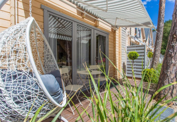 Terraza exterior en la cabaña de vacaciones en Pobierowo con silla colgante y toldo a rayas.