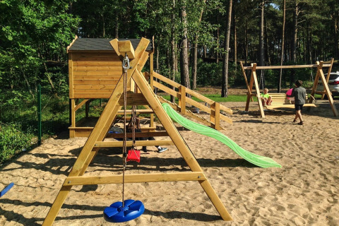 Playground at holiday cottage for 5 people in Pobierowo with slide and swings in a sandy area.