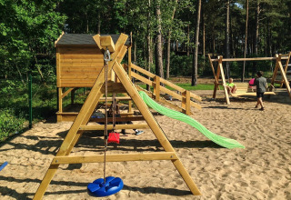 Playground at holiday cottage for 5 people in Pobierowo with slide and swings in a sandy area.