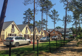 Vakantieverblijf voor 5 personen in Pobierowo, omringd door dennen, auto's geparkeerd en heldere lucht.