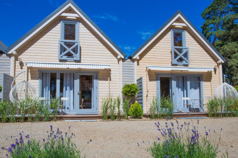 Two holiday cottages for 5 people in Pobierowo, Germany, featuring wooden exteriors and outdoor seating area.