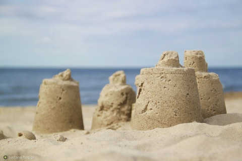Kleine zandkastelen op het strand met zee en lucht op de achtergrond, gefotografeerd tijdens glamping.