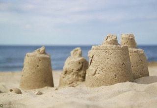 Kleine zandkastelen op het strand met zee en lucht op de achtergrond, gefotografeerd tijdens glamping.