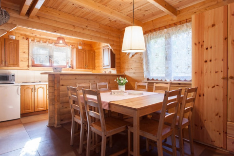 Houten eetruimte met acht stoelen en grote ramen in Wooden holiday cottages Pobierowo, Duitsland.