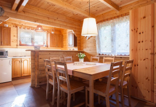 Houten eetruimte met acht stoelen en grote ramen in Wooden holiday cottages Pobierowo, Duitsland.