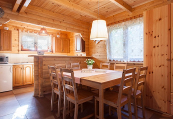Houten eetkamer met acht stoelen en groot raam in Wooden holiday cottages Pobierowo, Duitsland.