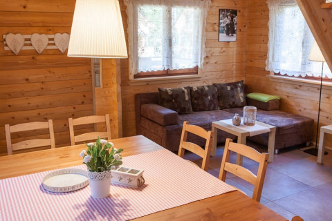 Knusse woonkamer met houten muren, eettafel en zetel in Wooden holiday cottages Pobierowo.