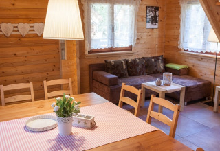 Gezellige woonkamer met houten wanden, eettafel en bank in Wooden holiday cottages Pobierowo.