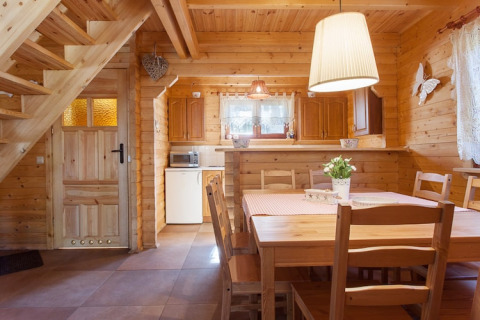 Gezellige houten vakantiewoning met eettafel, trap en keuken in Wooden holiday cottages Pobierowo.