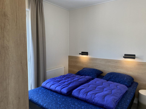 Moderne slaapkamer in Zonneweelde Lodge Deluxe op Camping Zonneweelde in Nederland, met blauw bedlinnen.