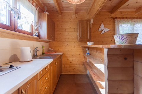 Gezellige houten keuken bij Wooden holiday cottages Pobierowo, met lichte kasten en een zonnige raamhoek.