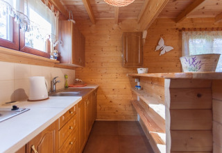 Gezellige houten keuken bij Wooden holiday cottages Pobierowo, met lichte kasten en een zonnige raamhoek.