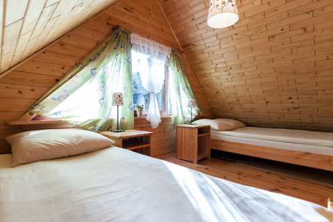 Gemütliches Schlafzimmer in einer Holzhütte mit zwei Einzelbetten und Dachschrägen in Pobierowo.