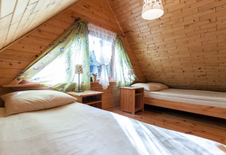 Slaapkamer in een houten vakantiehuisje met twee eenpersoonsbedden en schuin dak in Pobierowo, Duitsland.