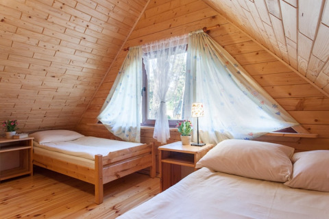 Knusse houten lodge slaapkamer met twee eenpersoonsbedden en raam in Wooden holiday cottages Pobierowo.