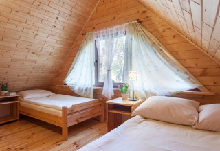 Gemütliches Schlafzimmer in einem Holzhaus mit zwei Einzelbetten, Fenster und Tageslicht bei Wooden holiday cottages Pobierowo.